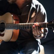Performer - A man playing the acoustic guitar