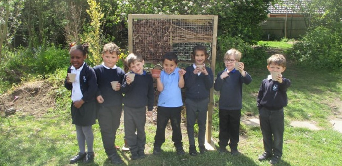 On their best beehive-iour - Year 1 children standing in front of the bee hotel made by site manager Aron Howlett