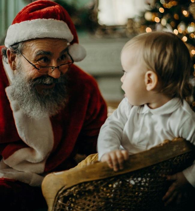 Santa attends to a child at his grotto. Credit: Pexels
