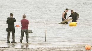 Bomb disposal team in action at Harwich Sailing club with WW2 V2 bomb in the mud.